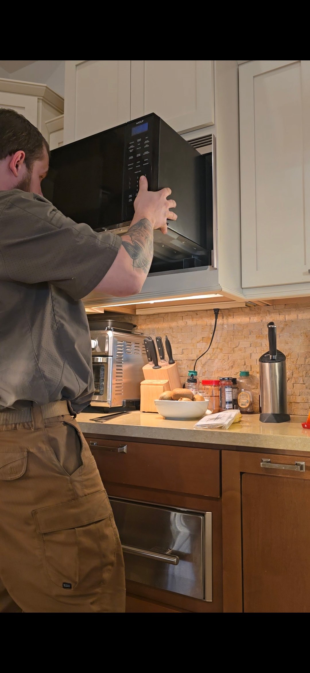 ProMaster technician servicing a built-in Wolf microwave