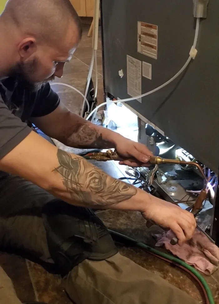 Technician brazing a refrigerant line on commercial refrigeration equipment
