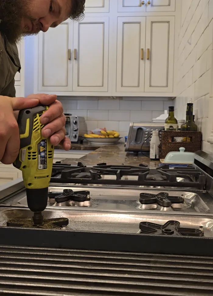 Technician repairing a gas cooktop burner assembly
