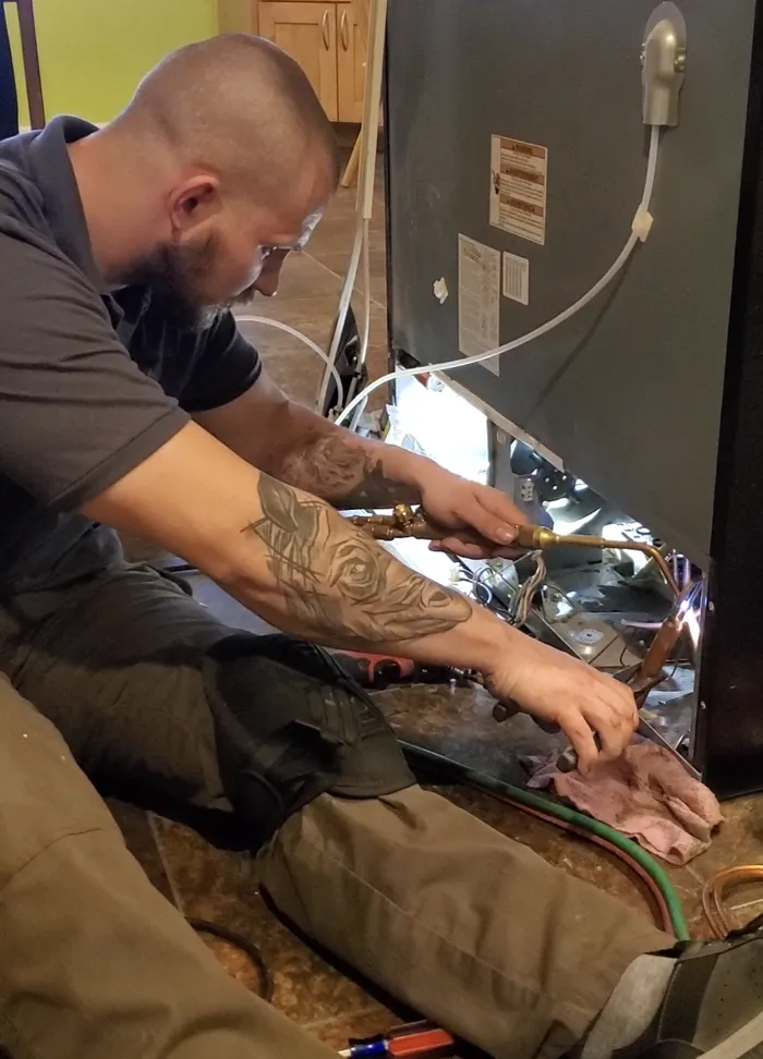 ProMaster technician brazing a refrigerant line during a refrigerator repair